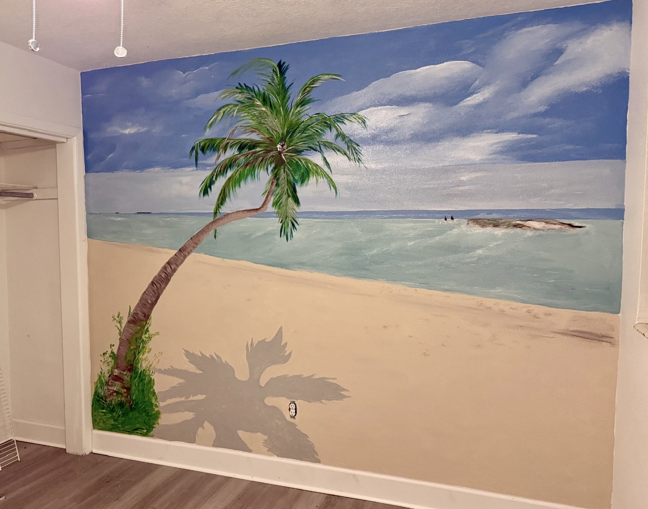 A beach mural with a leaning palm tree, sand, blue water, clouds, and a soft palm shadow.