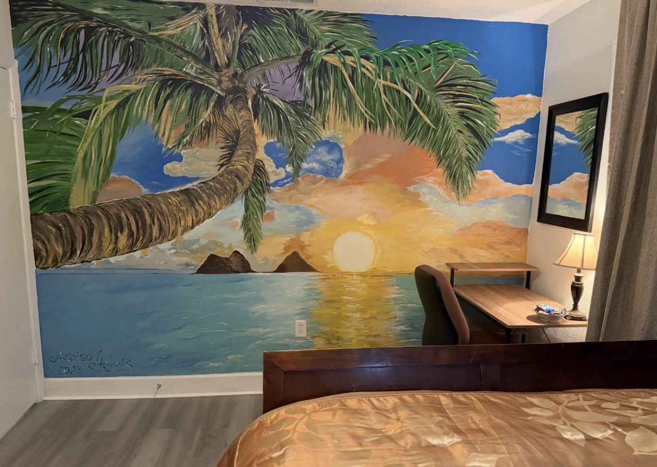 A bedroom wall mural with a large palm tree, ocean sunset, and island silhouettes.