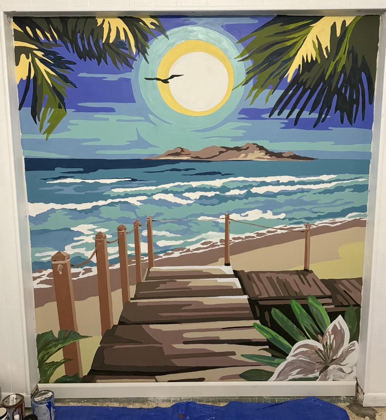 A colorful coastal mural showing a boardwalk leading to waves under a large moon and palm fronds.